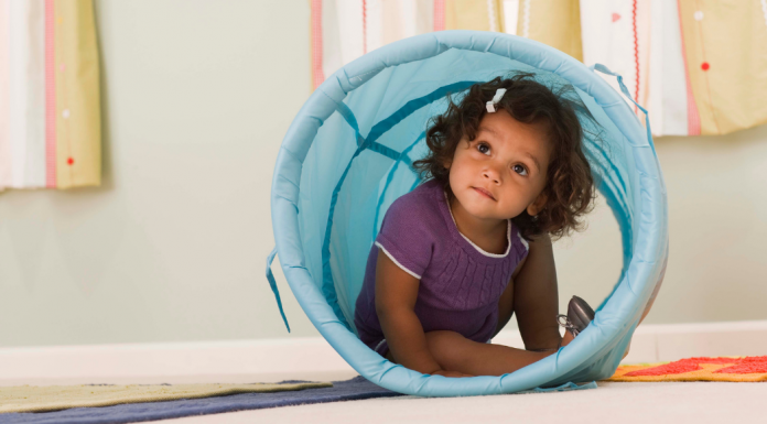 A toddler girl playing in a tunnel.