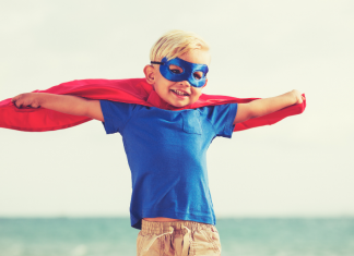 A boy dressed as a superhero with a cape.