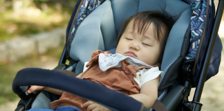 A baby napping in a stroller.