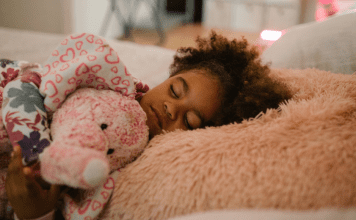 A little girl sleeping holding her stuffed animal.
