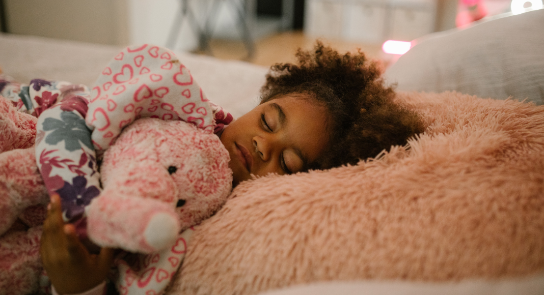 A little girl sleeping holding her stuffed animal. 