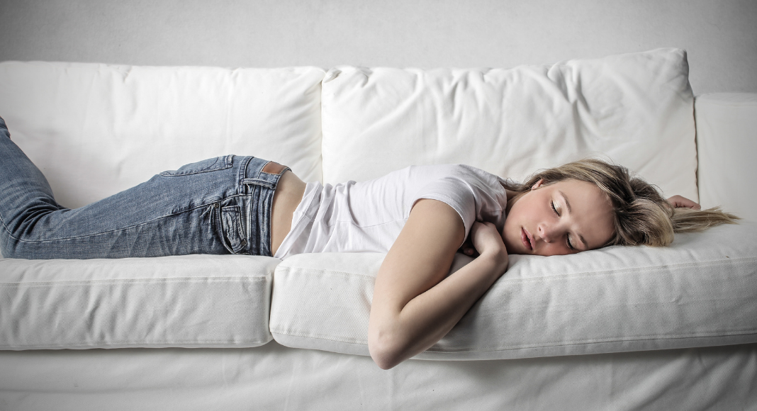 Teen girl sleeping on a couch.
