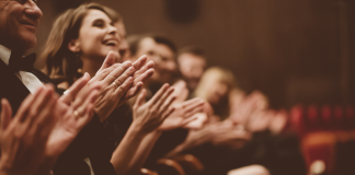 Audience members clapping in a theater.