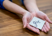 A woman holding a note "give."