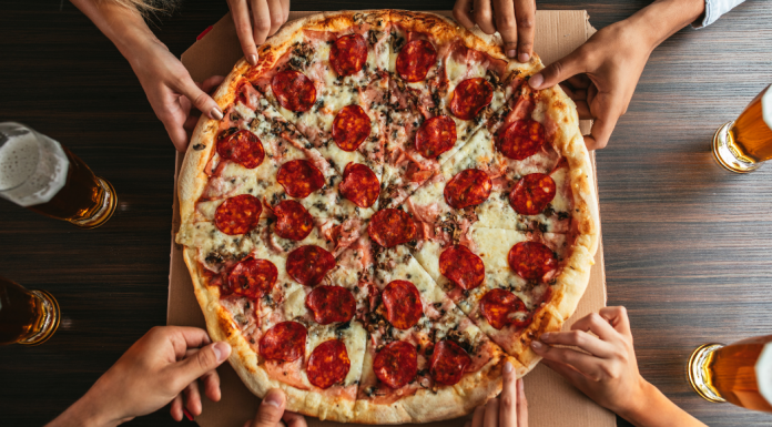 People reaching for pizza.