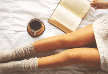 Womans legs in socks while reading a book and enjoying coffee.