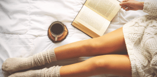 Womans legs in socks while reading a book and enjoying coffee.
