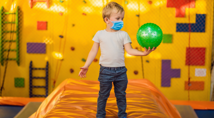 A boy holding a ball in an indoor play space.
