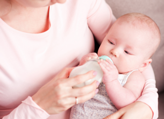 A woman bottle-feeding a baby.