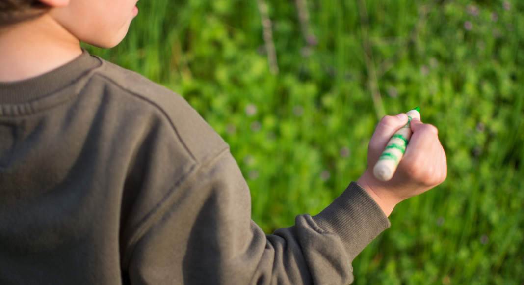 A boy holding a green crayon.