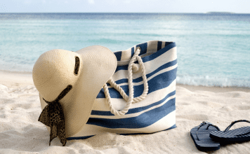 A full beach bag on the sand.