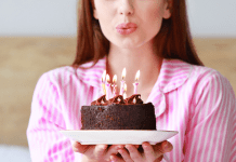 A woman blowing out a birthday candle on a cake.
