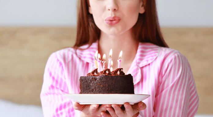 A woman blowing out a birthday candle on a cake.
