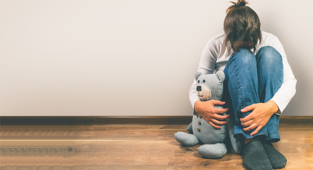 A woman holding a teddy bear after a miscarriage. 