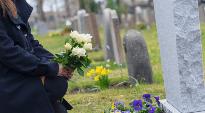 A woman putting flowers on a gravestone.
