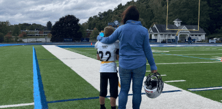 A mom with her arm around her son on a football field.