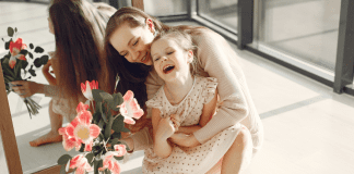 A mother holding flowers and her daughter.