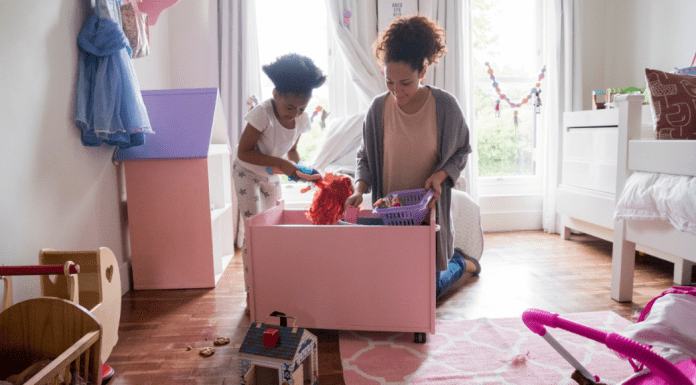 A girl helping her mom clean up the toys.