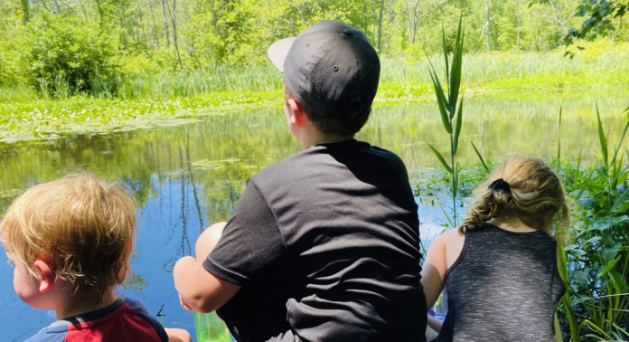 Three children looking out on a lake.