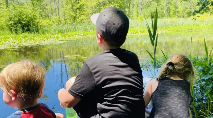 Three children looking out on a lake.