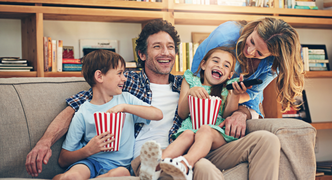 A family eating popcorn and watching a movie. 