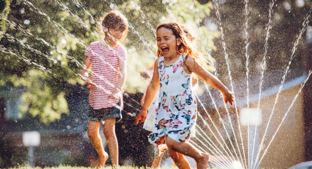 Kids running through a sprinkler. 